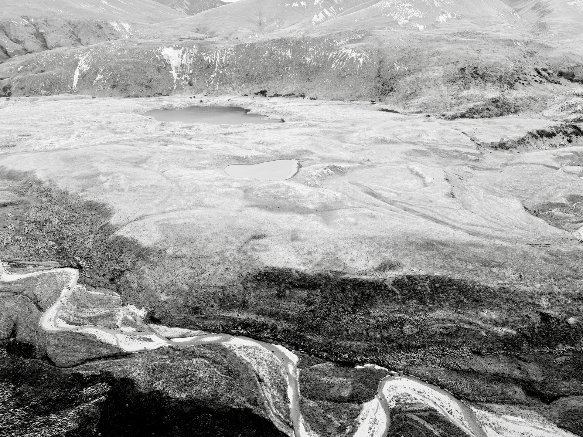 Black-and-white aerial view of a braided river and alpine tarns
