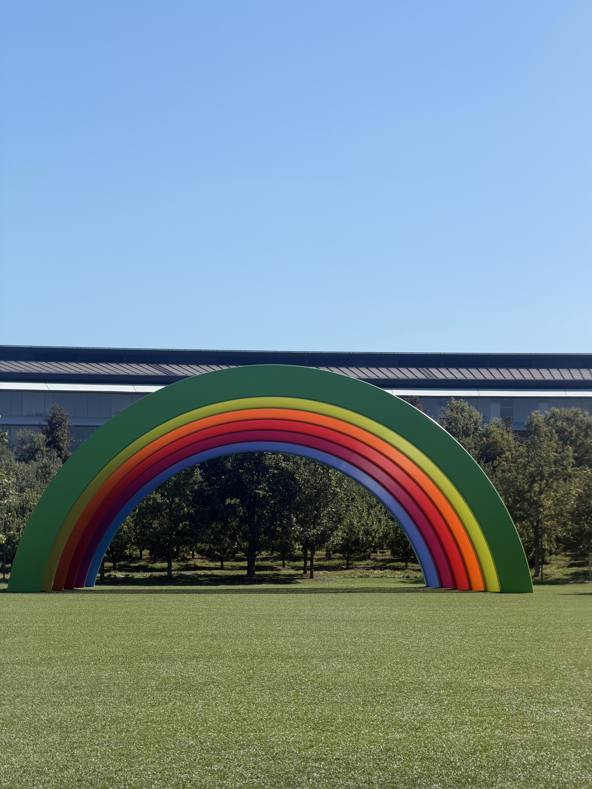 A rainbow arch sculpture on the lawn at Apple Park