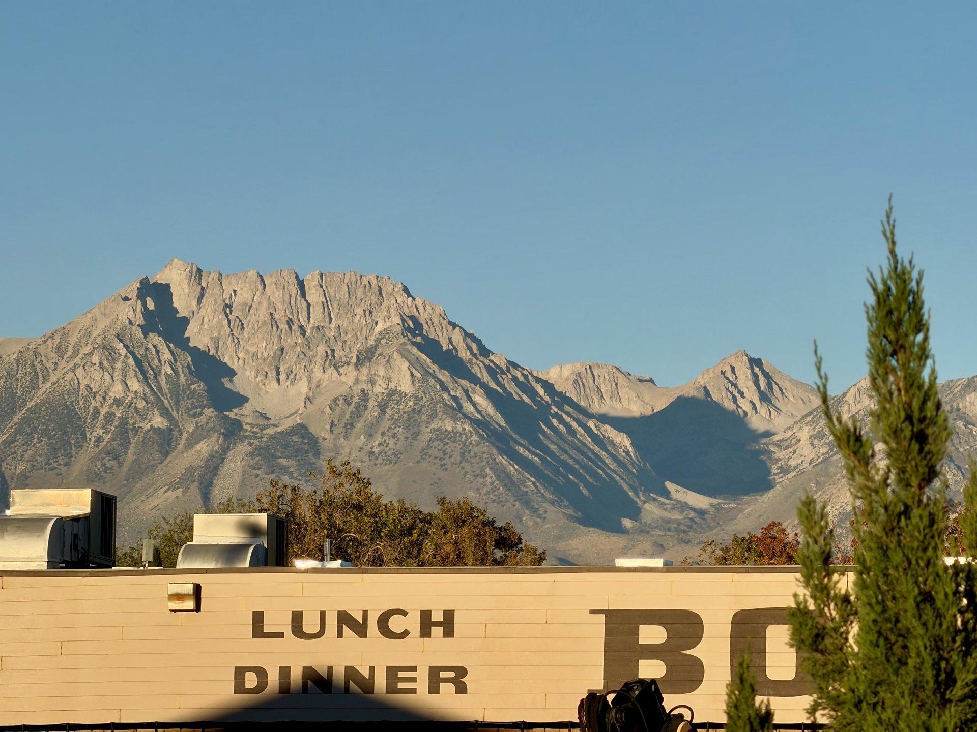 Granite peaks in morning light above a restaurant wall painted “Lunch Dinner”