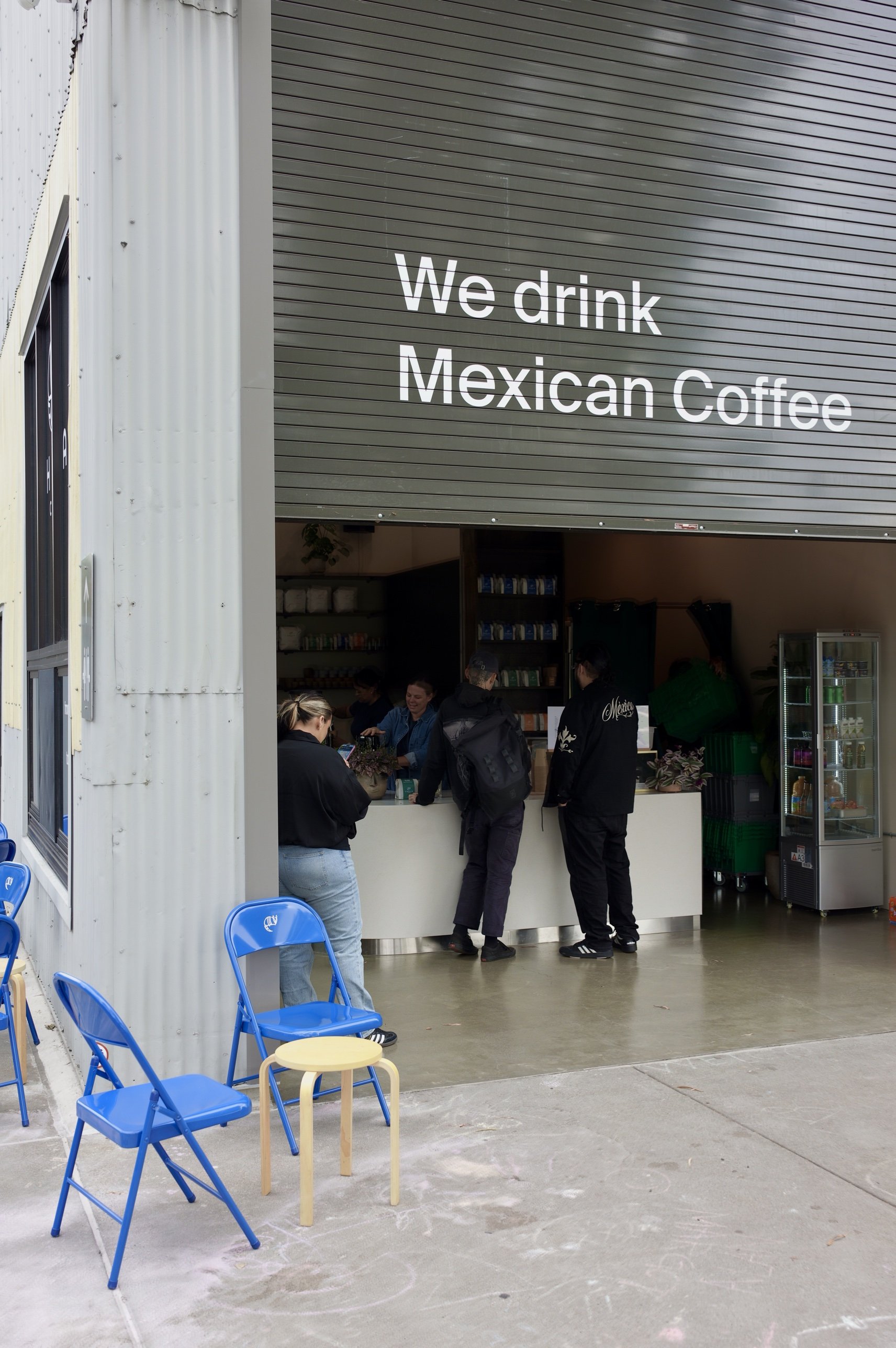Chula Café at Crane Cove Park, its roll-up door painted “We drink Mexican Coffee” over the counter